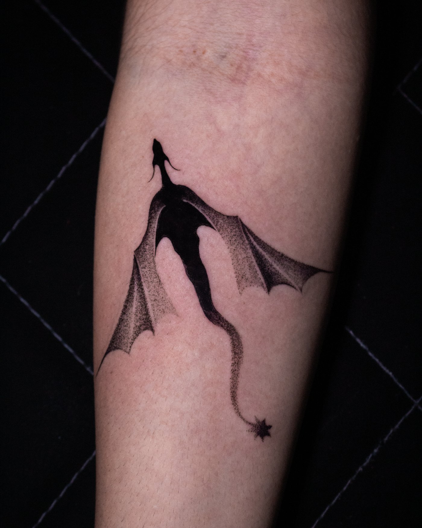 Tatuaje blackwork de Melody Goris: dragón en negro sólido, antebrazo.